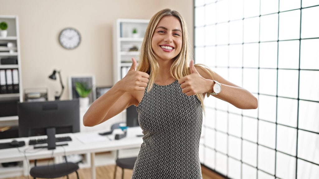 Young blonde woman business worker smiling confident doing thumbs up gesture at office