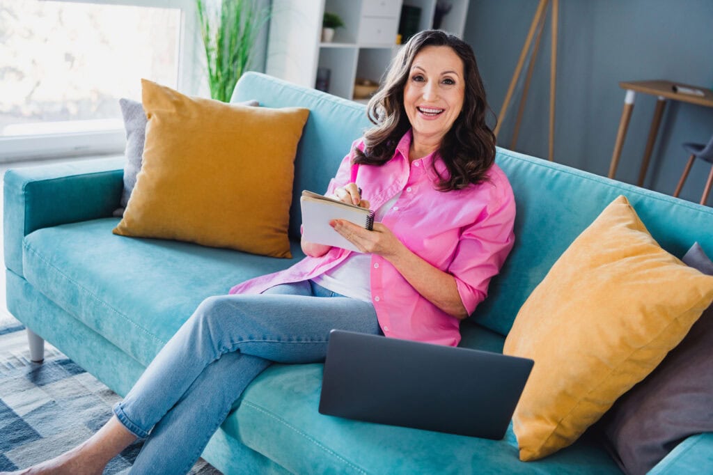 Woman sitting couch working from home writing tasks indoors