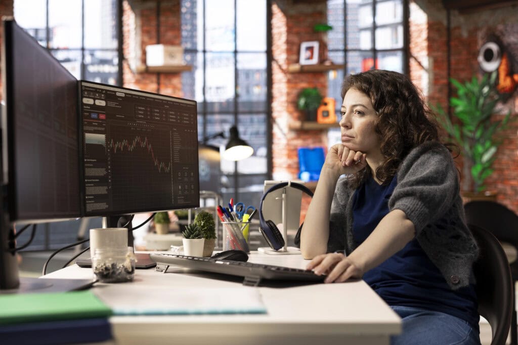 Stock market trader monitors real time charts on a multi screen setup, analyzing index trends and financial growth.