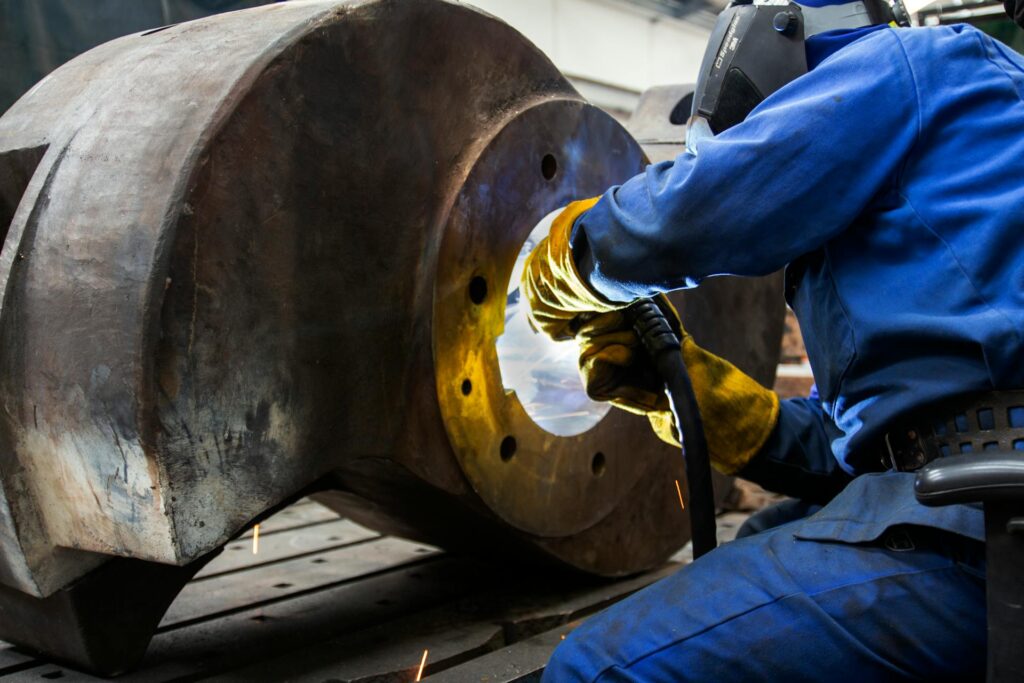 Industrial Welder at Work on Large Machine Part