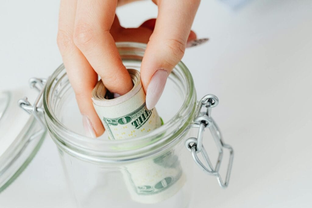 Close-Up Shot of a Person Saving Money in the Glass Jar