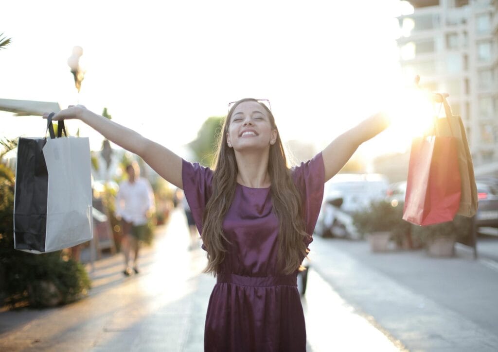 Woman raising her hands with shopping bags. 
