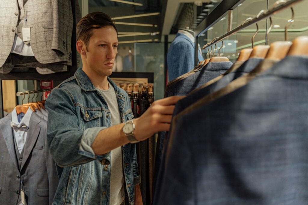 Man in Blue Denim Button Up Shirt Holding Black Pants