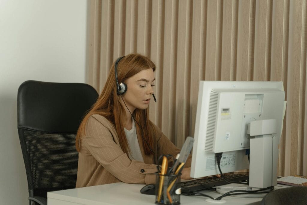 Woman in Headphones Sitting on Armchair and Working
