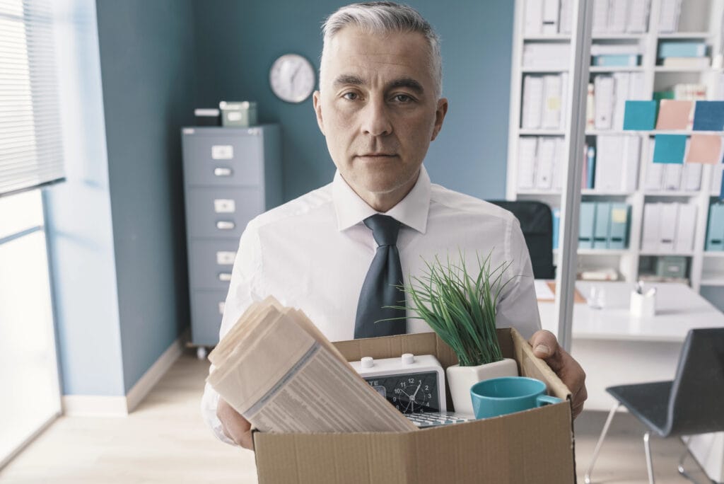 Businessman carrying a box with his belongings and leaving the office