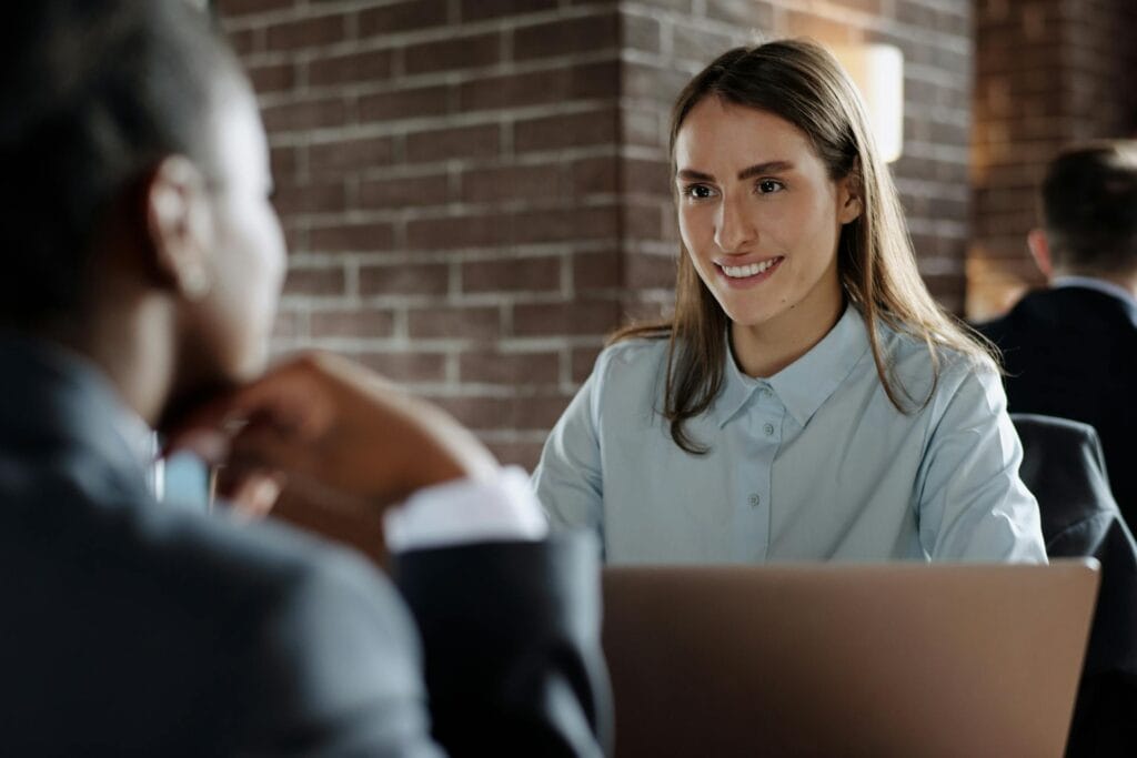 Woman and Man Sitting at a Table in a Restaurant with an Open Laptop