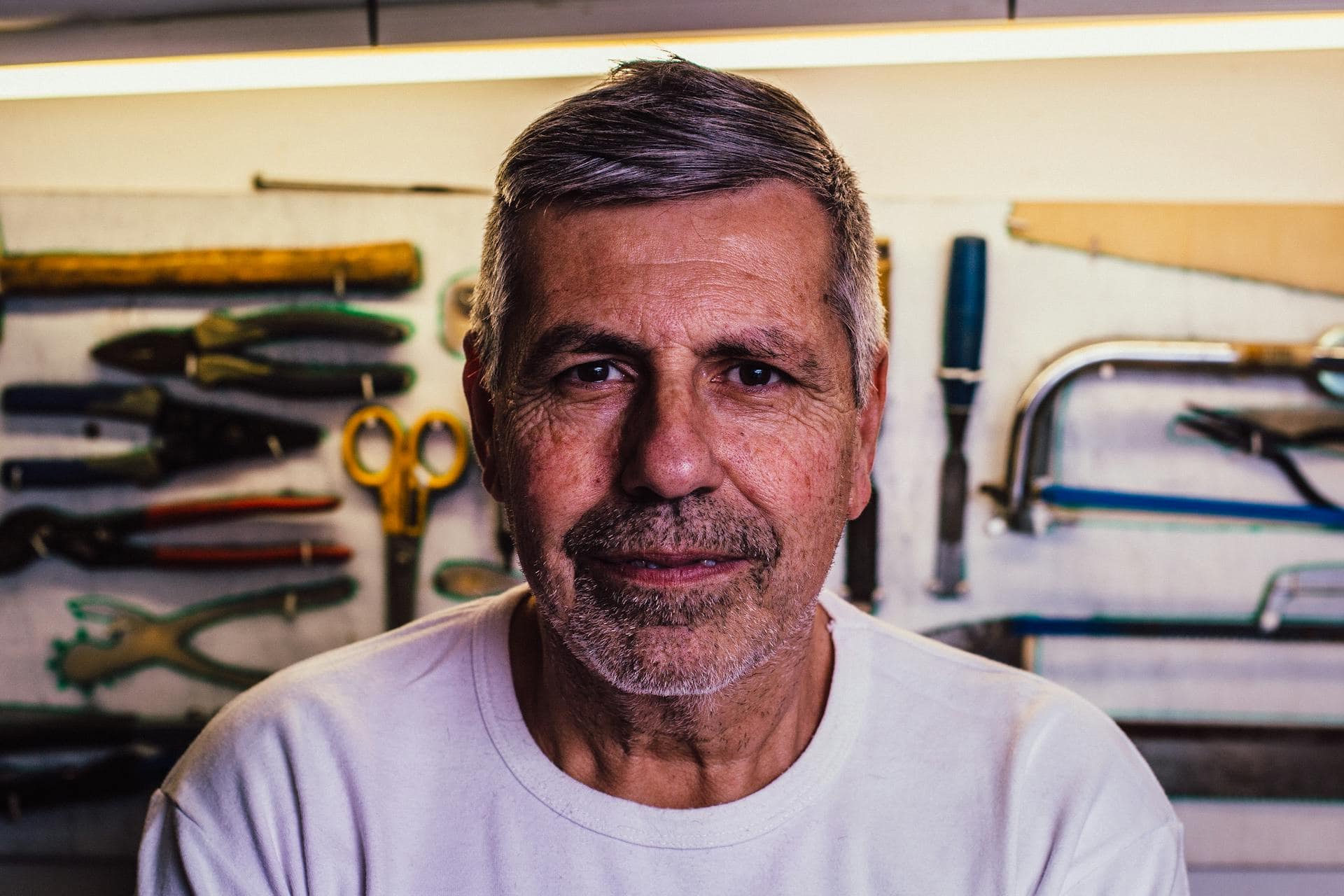 Man in White Crew-neck T-Shirt With Assorted Hand Tools in Background
