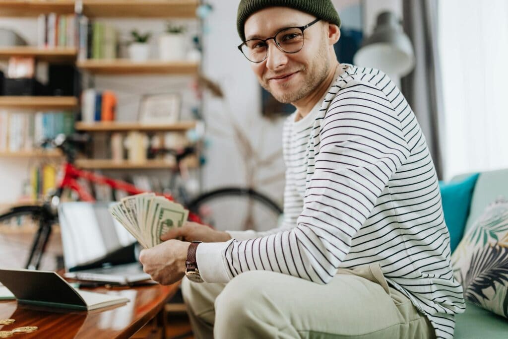 Smiling Man with Banknotes Sitting on Sofa in a Living Room