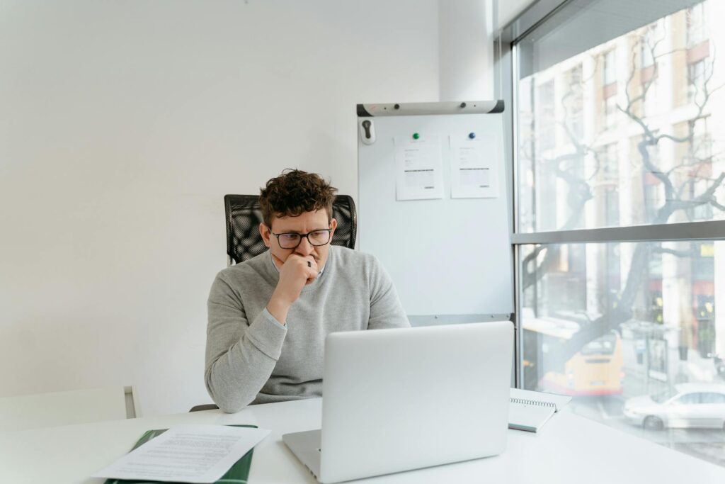 Man in Gray Sweater Wearing Eyeglasses while Working in the Office