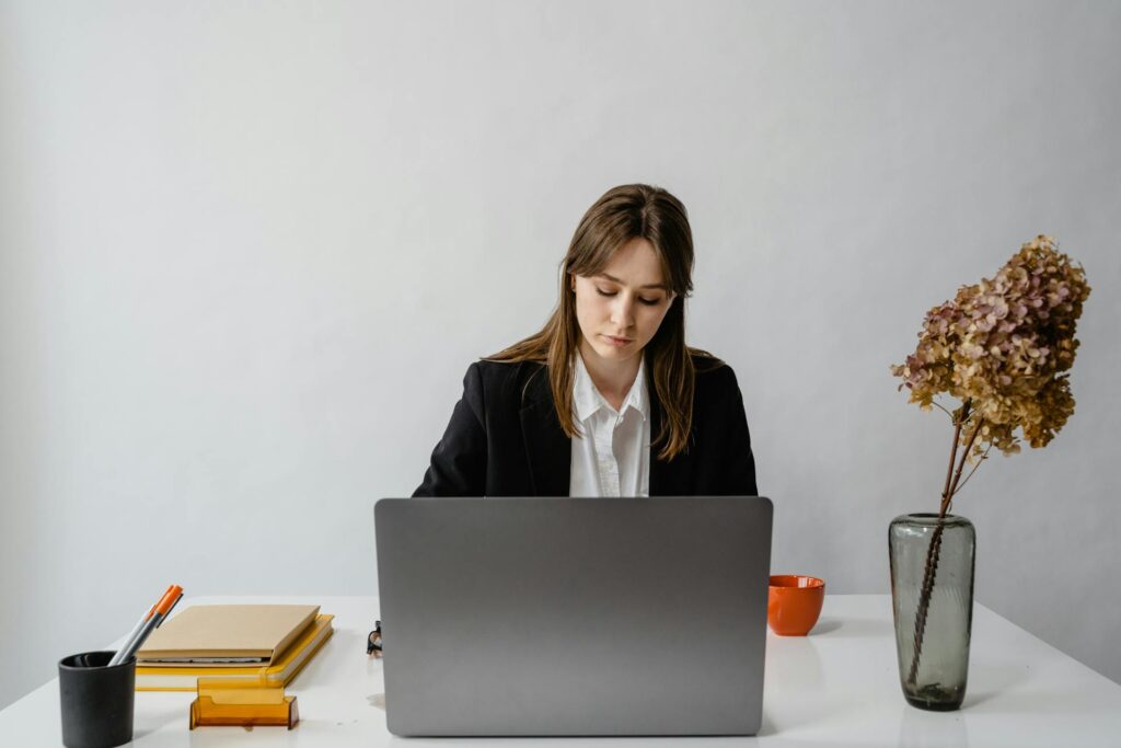 Woman Working on Laptop by White Desk