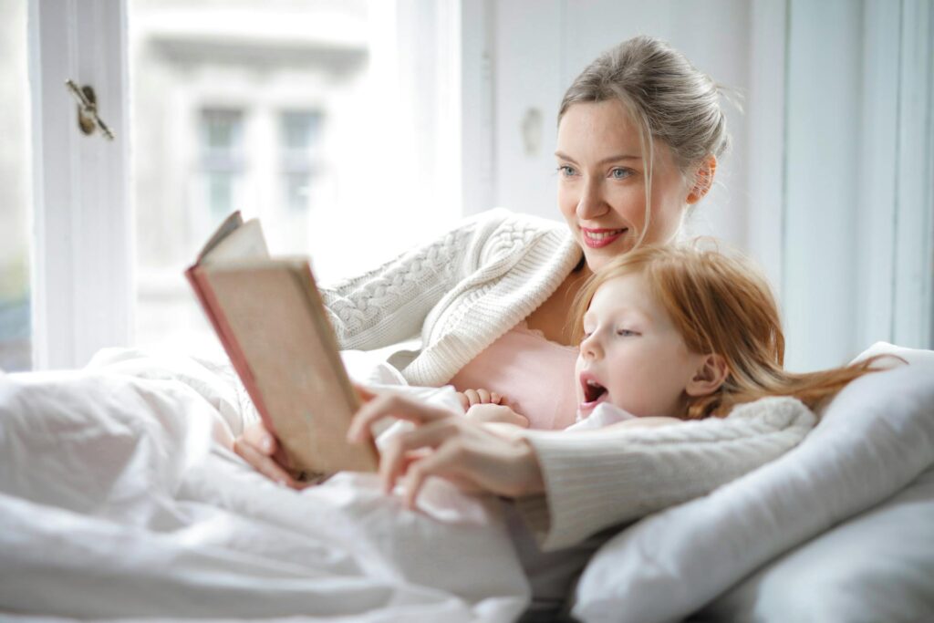 Mother and daughter reading book with interest in bed