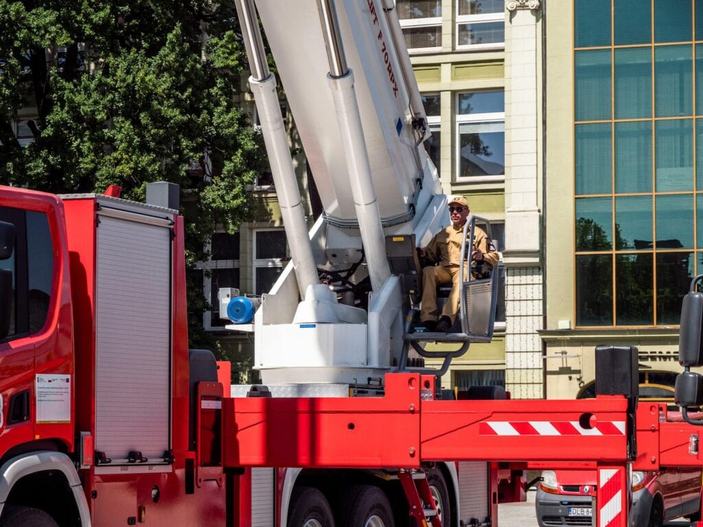 Construction Worker Operates Lift on Red Truck Outdoors