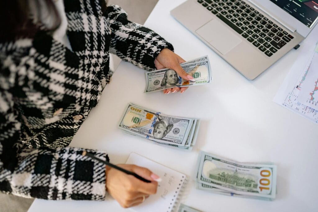 Hand of a Woman Holding Cash and a Pencil