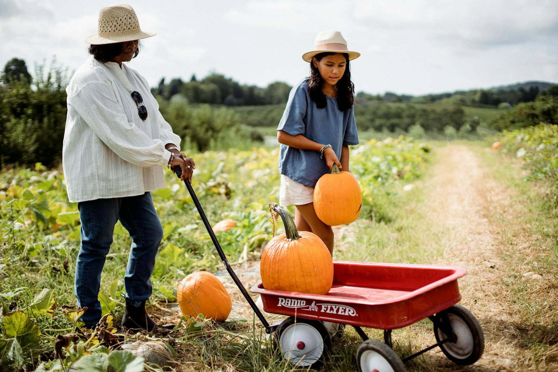 Hispanic woman with daughter in pumpkin field